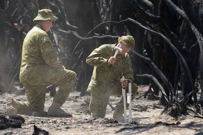 Lieutenant Kynan Lang from the 10th/27th Battalion placing crosses at the scene where his uncle and cousin died during a bushfire on Kangaroo Island.