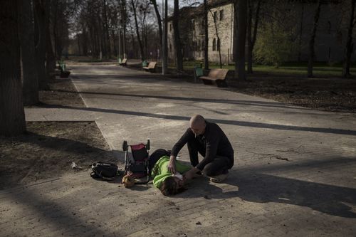 Oksana waits for an ambulance after being injured in a Russian attack at a public park in Kharkiv, Ukraine, Friday, April 15, 2022. (AP Photo/Felipe Dana)