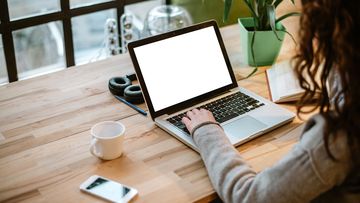 Woman working on laptop with white screen in modern office.