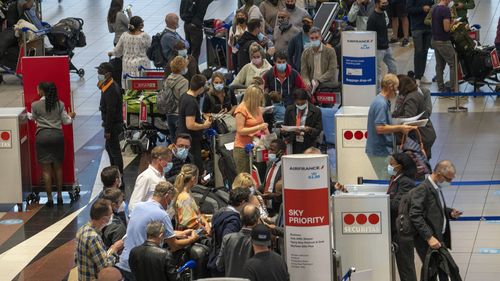 People lineup to get on the Air France flight to Paris at OR Tambos airport in Johannesburg, South Africa, Friday Nov. 26, 2021. 