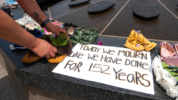 Stephanie Gilpin, whose parents, aunts and uncles were sent to residential schools, smooths out the cedar that she placed in a pair of moccasins at the Centennial Flame on Parliament Hill in Ottawa, Ontario, in memory of the 215 children whose remains were found at the grounds of the former Kamloops Indian Residential School on Sunday, May 30, 2021.