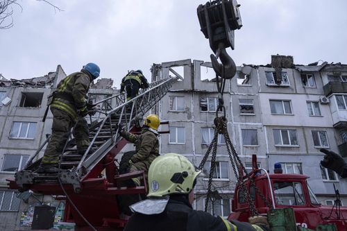 Rescue workers climb by ladder as they clear the rubble of the residential building which was destroyed by a Russian rocket in Pokrovsk, Ukraine, Wednesday, Feb. 15, 2023