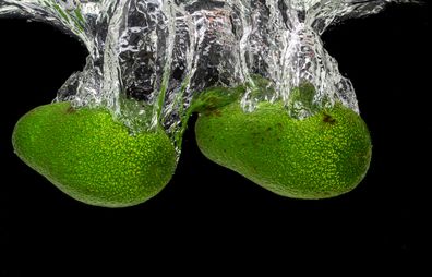 Two avocados submerged in water.