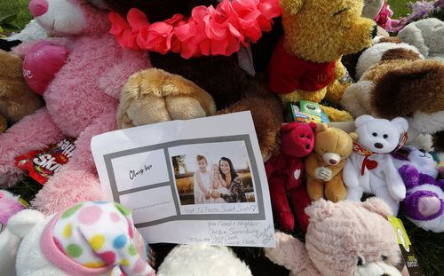 A photograph sits amid the tributes as they grow outside the home.