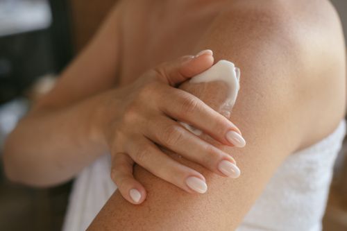 A personification applying sunscreen to their arms.