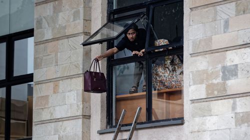 A woman throws her handbag out of the window of a luxury hotel as she flees the hotel complex.