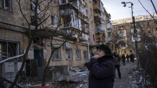A woman looks at residential buildings damaged by a bomb in Kyiv, Ukraine, Friday, March 18, 2022. 