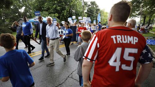 Bernie Sanders waves to a Donald Trump supporter during a parade in Iowa.