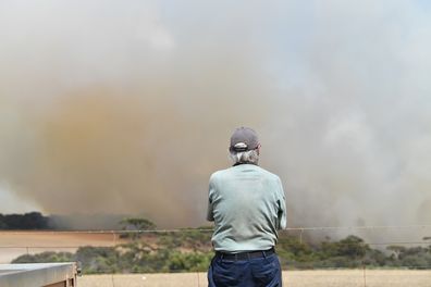 Local farmer John Stanton looks on as bushfires sweep through Stokes Bay on Kangaroo Island, southwest of Adelaide, Thursday, January 9, 2020. A convoy of Army vehicles, transporting up to 100 Army Reservists and self-sustainment supplies, are on Kangaroo Island as part of Operation Bushfire Assist at the request of the South Australian Government. (AAP Image/David Mariuz) 