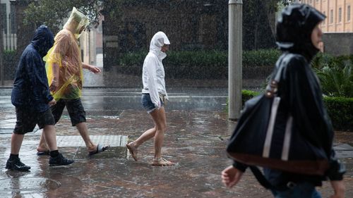 Pedestrians walk through the heavy rainfall in Sydney's CBD.