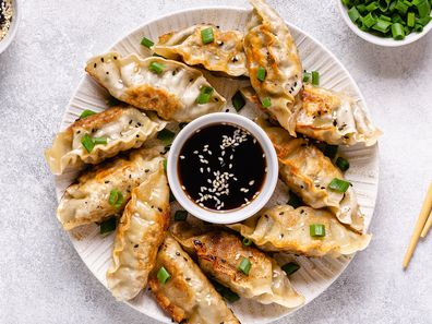 Fried dumplings gyoza with soy sauce, and chopsticks, top view.