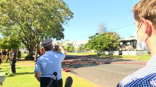 A fire has erupted behind a police officer while he was talking to a news crew about an unrelated deadly fire