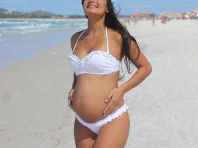 Stock photo of a pregnant woman in a bikini at the beach.