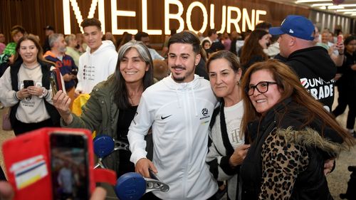 Marco Tilio of the Socceroos poses with fans at Melbourne Airport.