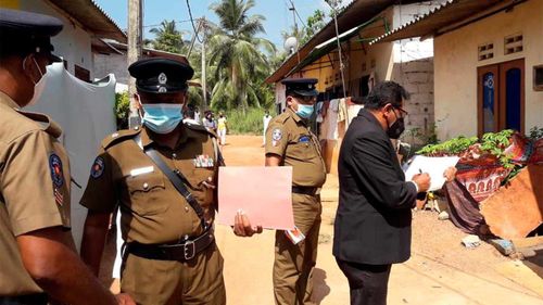 Sri Lankan magistrate Wasantha Ramanayake, right and police officers inspect outside a house where a nine-year-old girl was canned to death in Delgoda, Sri Lanka.