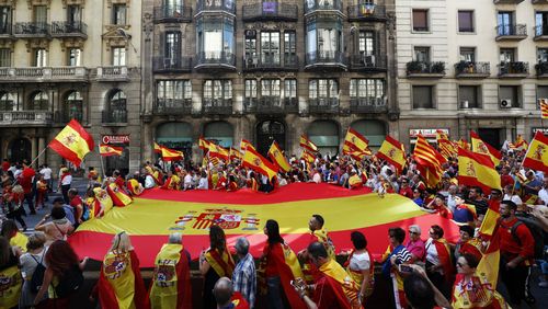 Protestors carry a giant Spanish flag during a rally in favour of the unity of Spain in Barcelona. (AAP)