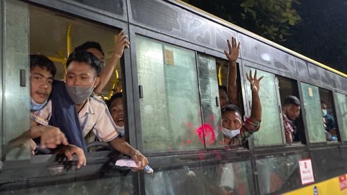 People wave from a bus after being released from Insein Prison in Yangon. 