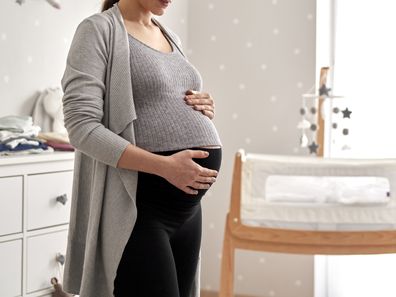 Pregnant woman standing in baby nursery of her home