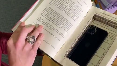 A phone hidden inside the pages of a book.