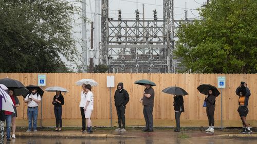 Rain falls as voters line up to cast their ballots on Election Day at the West Gray Multi-Service Center in Houston. 