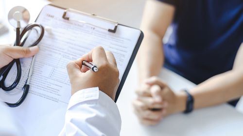 Close-up of a male doctor hand hold a silver pen and showing pad in hospital. Doctor giving prescription to the patient and filling up medical form at a clipboard