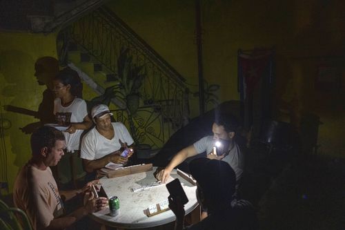 People play dominoes by flashlight during a blackout in Havana, Cuba, Wednesday, Sept. 28, 2022. 