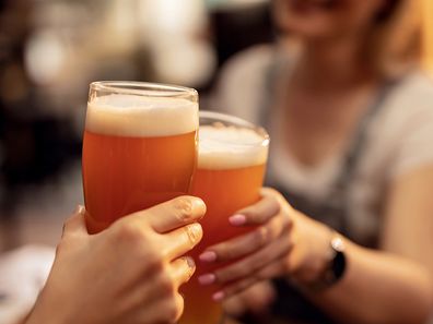 Two people toasting beer in a bar