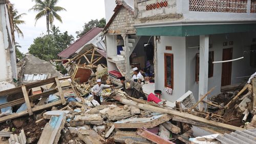 People salvage items from the rubble at the ruins of Al Buroq Islamic Boarding School which was badly damaged during Monday's earthquake, in Cianjur, West Java, Indonesia, Wednesday, Nov. 23, 2022. More rescuers and volunteers were deployed Wednesday in devastated areas on Indonesia's main island of Java to search for the dead and missing from an earthquake that killed hundreds of people. (AP Photo/Rangga Firmansyah)