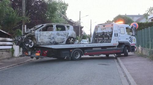 A burnt car is towed from the damaged residence of Mayor of L'Hay-les-Roses Vincent Jeanbrun, which was ram-raided and set alight while Jeanbrun's wife and children were asleep inside. 