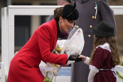 Kate, Princess of Wales gets flowers from a little girl ahead of a St David's Day parade with members of the 1st Battalion, The Welsh Guards in Windsor England, Wednesday, March 1, 2023. 