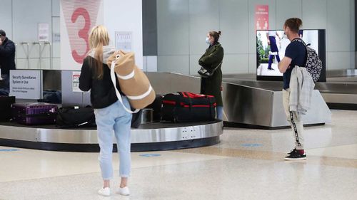 Passengers wait for their luggage.