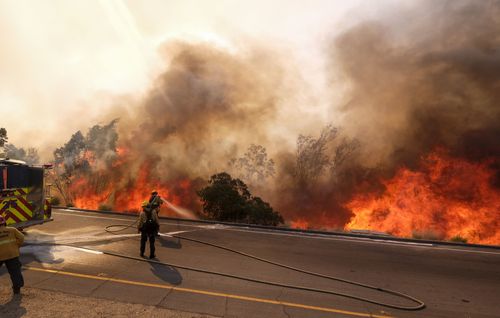 A firefighter battles a fire along the Ronald Reagan Freeway in Simi Valley.