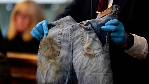 Sgt. Yuriy Bukhenik, of the Massachusetts State Police, holds the stained jeans cut from Boston Police officer John O'Keefe as he returns to the witness stand in the murder retrial of Karen Read in Norfolk Superior Court, Monday, May 12, 2025, in Dedham, Mass. (Pat Greenhouse/The Boston Globe via AP, Pool)