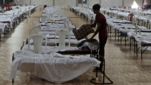 A labour makes bedding inside a makeshift quarantine facility for patients diagnosed with the coronavirus disease (COVID-19) in Mumbai, India, Friday, June 12, 2020.(AP Photo/Rafiq Maqbool)