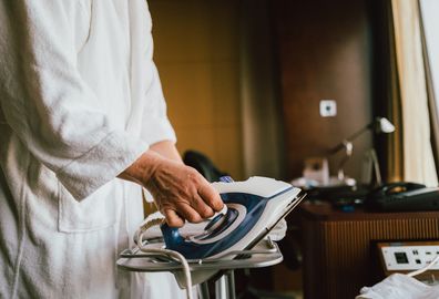 Businessman Ironing Shirt at Hotel Room during Business Travel