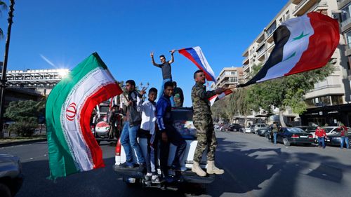 Syrian government supporters wave national flags and chant slogans against US President Trump during demonstrations. (AP)