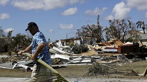 Rob Brehm cleans up debris from his home as a demolished house sits across the street after Hurricane Irma in Goodland. (Associated Press)