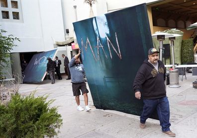 Crew members hold signs for the new movie "The wolf man" After the first show was cancelled