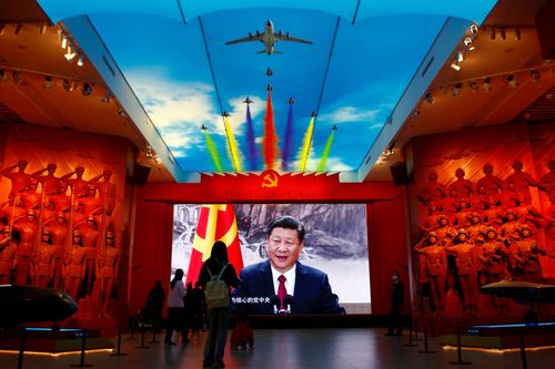FILE PHOTO: Visitors stand in front of a giant screen displaying Chinese President Xi Jinping next to a flag of the Communist Party of China, at the Military Museum of the Chinese People's Revolution in Beijing, China.