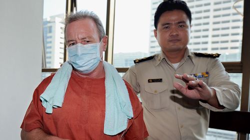 Kinch escorted by a Thai court official as he arrives at the crime court in Bangkok on November 27, 2009. (AFP)