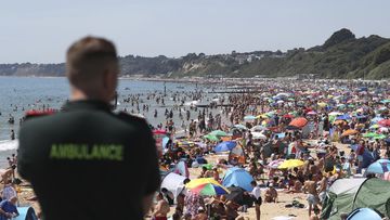 An ambulance officer looks out at people crowded on the beach in Bournemouth, England, on June 25, after coronavirus lockdown restrictions were relaxed.