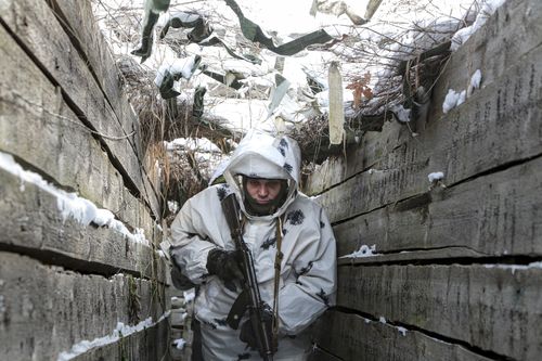 An armed serviceman walks along a trench on the territory controlled by pro-Russian militants on the frontline with Ukrainian government forces near Spartak village in Yasynuvata district of Donetsk region, eastern Ukraine, Thursday, Jan. 27, 2022. 