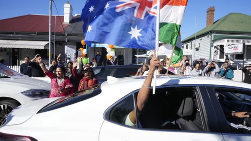 People dance in the street and wave Indian and Australian flags from cars as they wait hoping Indian Prime Minister Narendra Modi might visit the suburb of Harris Park in Sydney, Tuesday, May 23, 2023. Modi has arrived in Sydney for his second Australian visit as India's prime minister and told local media he wants closer bilateral defense and security ties as China's influence in the Indo-Pacific region grows. (AP Photo/Rick Rycroft)