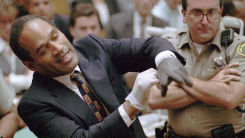 O.J. Simpson grimaces as he tries on one of the leather gloves prosecutors say he wore the night his ex-wife Nicole Brown Simpson and Ron Goldman were murdered, during the Simpson double-murder trial.