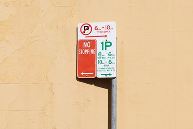 White and red metal road signs with a painted wall behind.