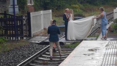 Couple take wedding photos on railway