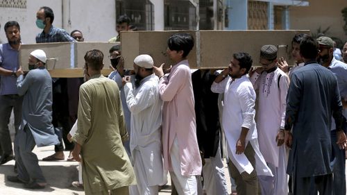 People carry the casket of the victims of Friday's plane crash for funeral prayers in Karachi, Pakistan, Saturday, May 23, 2020