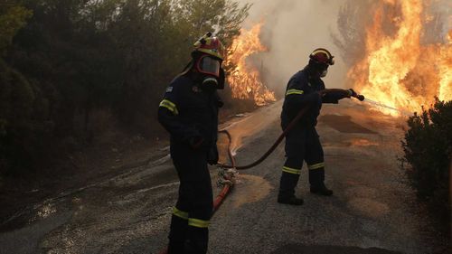 Firefighters try to extinguish a wildfire in Penteli, a northern suburb of Athens, Greece. (AAP)