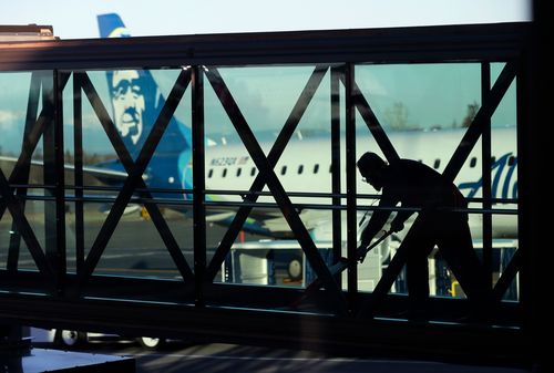 A worker cleans a jet bridge before passengers board Alaska Airlines flight 