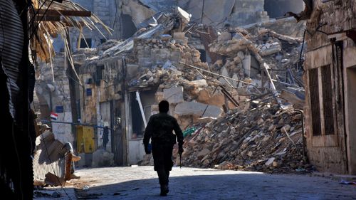 A Syrian pro-government fighter walks past damaged buildings in the Bab al-Nasr district of Aleppo's Old City on December 9, 2016. (AFP)